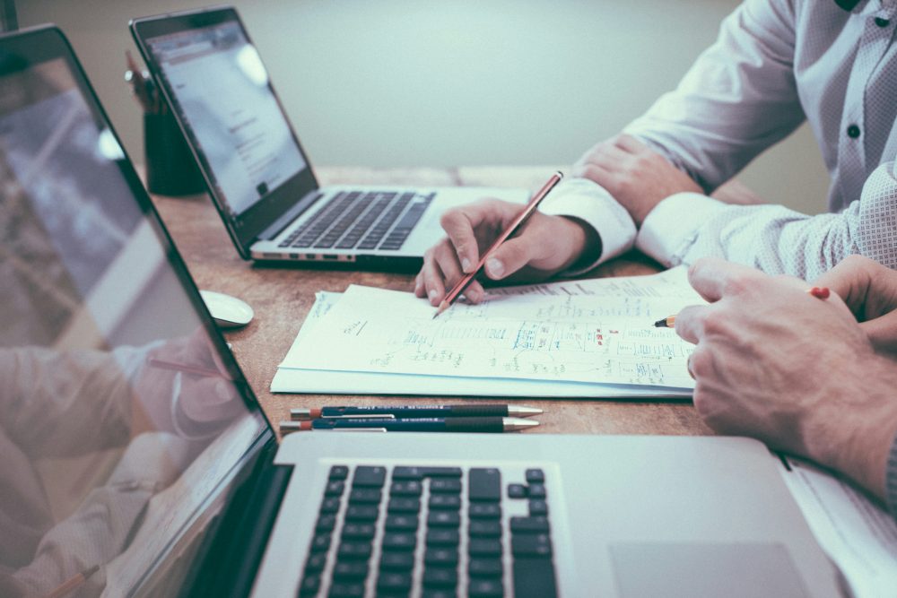 Unternehmensberater sitzen vor Laptop und schreiben auf Papier