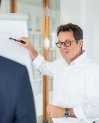 Unternehmensberater Andreas Kuchenbecker zeigt auf Whiteboard