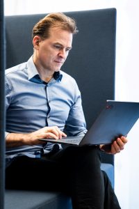 Unternehmensberater Georg Böning sitzt mit Laptop auf dem Schoß