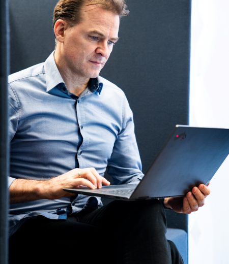 Unternehmensberater Georg Böning sitzt mit Laptop auf dem Schoß