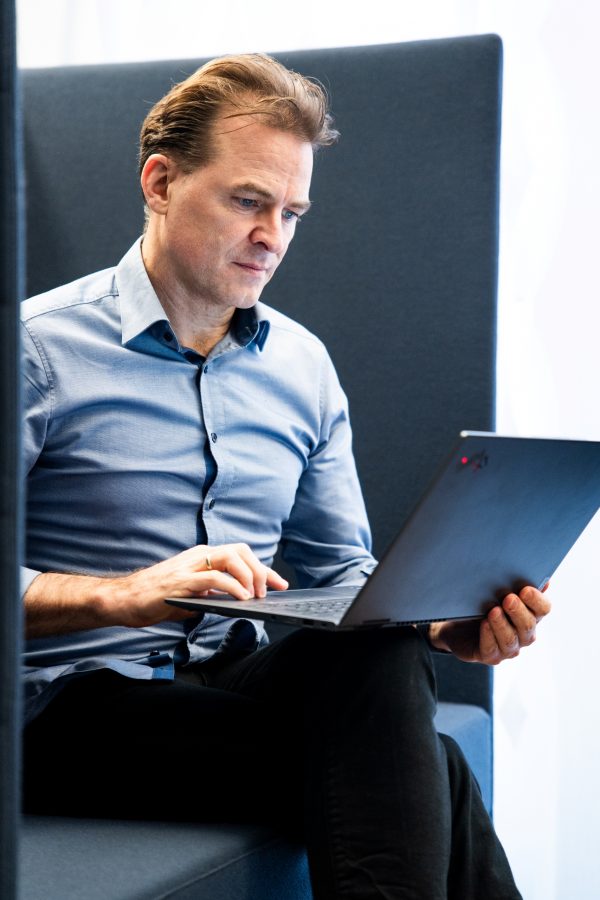 Unternehmensberater Georg Böning sitzt mit Laptop auf dem Schoß