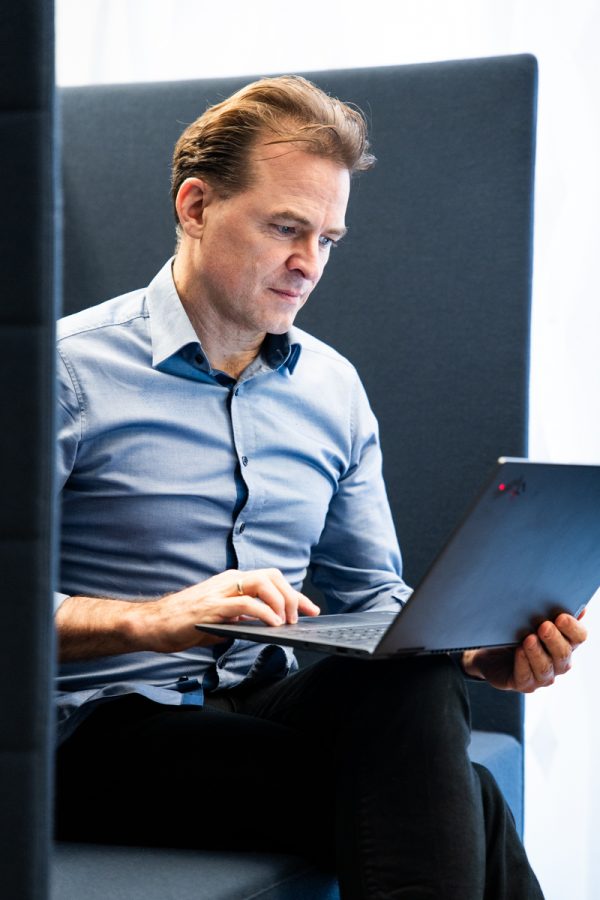 Unternehmensberater Georg Böning sitzt mit Laptop auf dem Schoß